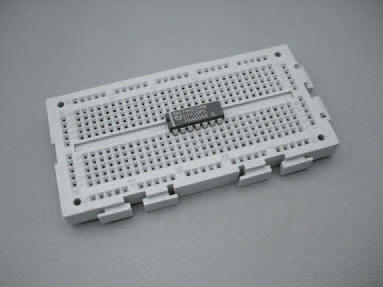 An IC mounted on a breadboard. The breadboard is designed so that an IC can be mounted without shorting the pins